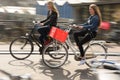 Two Women Ride their bikes to work in Amsterdam, Netherlands Royalty Free Stock Photo