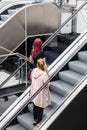 Two women riding an escalator at a shopping mall or shopping centre