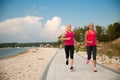 Two women athlets running on the beach - early morning summer w Royalty Free Stock Photo