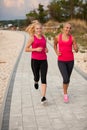 Two women athlets running on the beach - early morning summer w Royalty Free Stock Photo