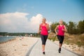 Two women athlets running on the beach - early morning summer w