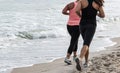 Two women running on beach by water