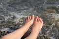 Two women`s feet on a shingle beach by the sea