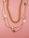 Two women`s golden necklaces on shimmering pink background