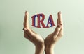 Two women`s hands hold the word IRA against a mint background Royalty Free Stock Photo