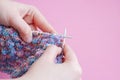 Two women`s hands knitting needles from pink and blue yarn on a pink background Royalty Free Stock Photo