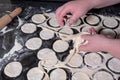Two women`s hands remove the dough strips from the circles cut from the rolled dough