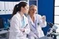 Two women scientists looking sample at laboratory