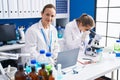 Two women scientists using microscope and laptop at laboratory Royalty Free Stock Photo