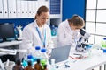 Two women scientists using microscope and laptop at laboratory Royalty Free Stock Photo