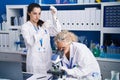 Two women scientists using microscope measuring liquid at laboratory Royalty Free Stock Photo