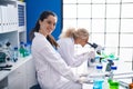 Two women scientists using microscope working at laboratory Royalty Free Stock Photo