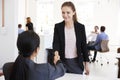 Two women shaking hands at a meeting in an open plan office Royalty Free Stock Photo