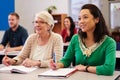 Two women sharing a desk at an adult education class look up Royalty Free Stock Photo