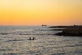 Two women sharing paddle board at sunset on calm waters in mediterranean sea in cyprus. Two girls on paddling on SUP Royalty Free Stock Photo