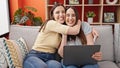 Two women shopping with laptop and credit card hugging each other at home Royalty Free Stock Photo