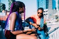 Two women sisters sitting outdoor talking and using smartphone Royalty Free Stock Photo