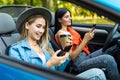 Two women sit in car in front seats and use phones in convertible car Royalty Free Stock Photo