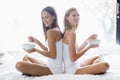 Two women sitting on bed eating cereal Royalty Free Stock Photo