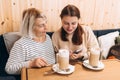 Two women sitting in a cafe, talking and drinking coffee. Female friends having coffee, smiling and gossip. Royalty Free Stock Photo