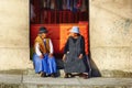 Two Women Sitting In Front Of A Shop in Bolivia