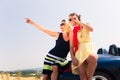 Two women sitting on hood of convertible car Royalty Free Stock Photo