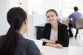 Two women sitting at an interview in an open plan office Royalty Free Stock Photo
