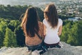 Two women sitting on the peak and lookin on city landscape