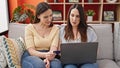 Two women sitting on sofa shopping with laptop and credit card at home Royalty Free Stock Photo