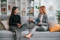 Two women is sitting on the sofa and talking. Casual and formal clothes Royalty Free Stock Photo