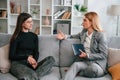 Two women is sitting on the sofa and talking. Casual and formal clothes Royalty Free Stock Photo