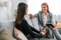 Two women is sitting on the sofa and talking. Casual and formal clothes Royalty Free Stock Photo