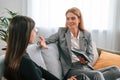 Two women is sitting on the sofa and talking. Casual and formal clothes Royalty Free Stock Photo