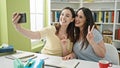 Two women sitting on table studying make selfie by smartphone at library university Royalty Free Stock Photo