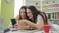 Two women sitting on table studying using smartphone at library university Royalty Free Stock Photo