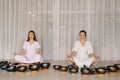 Two women are sitting with Tibetan bowls in the lotus position before a yoga class in the gym Royalty Free Stock Photo