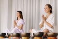 Two women are sitting with Tibetan bowls in the lotus position before a yoga class in the gym Royalty Free Stock Photo