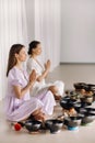 Two women are sitting with Tibetan bowls in the lotus position before a yoga class in the gym Royalty Free Stock Photo