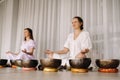 Two women are sitting with Tibetan bowls in the lotus position before a yoga class in the gym Royalty Free Stock Photo
