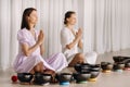 Two women are sitting with Tibetan bowls in the lotus position before a yoga class in the gym Royalty Free Stock Photo