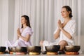 Two women are sitting with Tibetan bowls in the lotus position before a yoga class in the gym Royalty Free Stock Photo