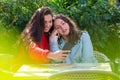 Two women with smartphone  sit in outdoor cafe, sharing the news and  laughing, girls party concept Royalty Free Stock Photo