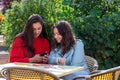 Two women with smartphone  sit in outdoor cafe, sharing the news and  laughing, girls party concept Royalty Free Stock Photo