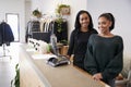 Two women smiling behind the counter in clothing store Royalty Free Stock Photo