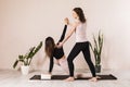 Two women in sportswear practicing yoga doing a low lunge on one leg with a twist or Anjanasana or Anjaneyasana Royalty Free Stock Photo