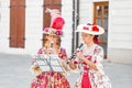 Two women street performers in medieval dresses playing on flutes Bach`s works for donations
