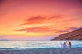 Two women taking photos of the amazing sunset at the beach of Matala, Crete