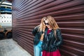 Two Women Talking in the City.Outdoor lifestyle portrait of two best friends hipster girls wearing stylish Leather Royalty Free Stock Photo