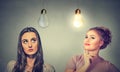 Two women thinking looking up at light bulbs. Royalty Free Stock Photo