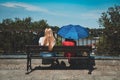 Two women with umbrellas sitting on a bench